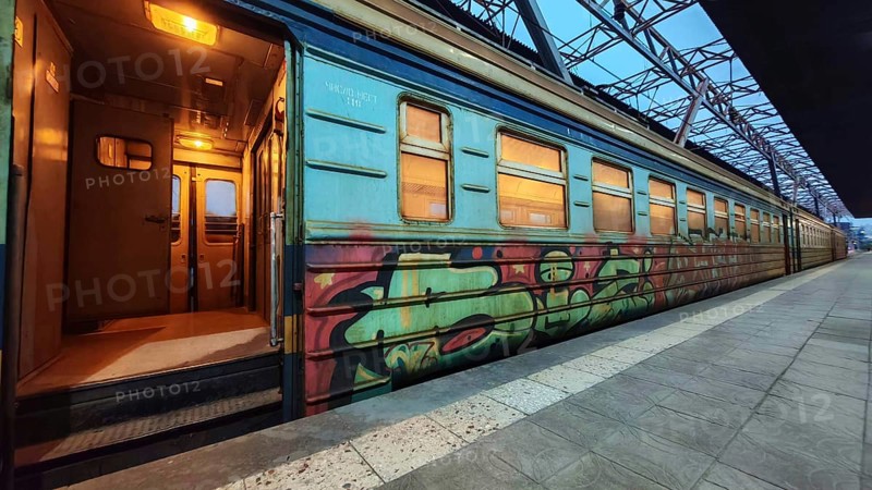 A train with graffiti stands on the platform with open doors and cozy lights, Yerevan, Armenia