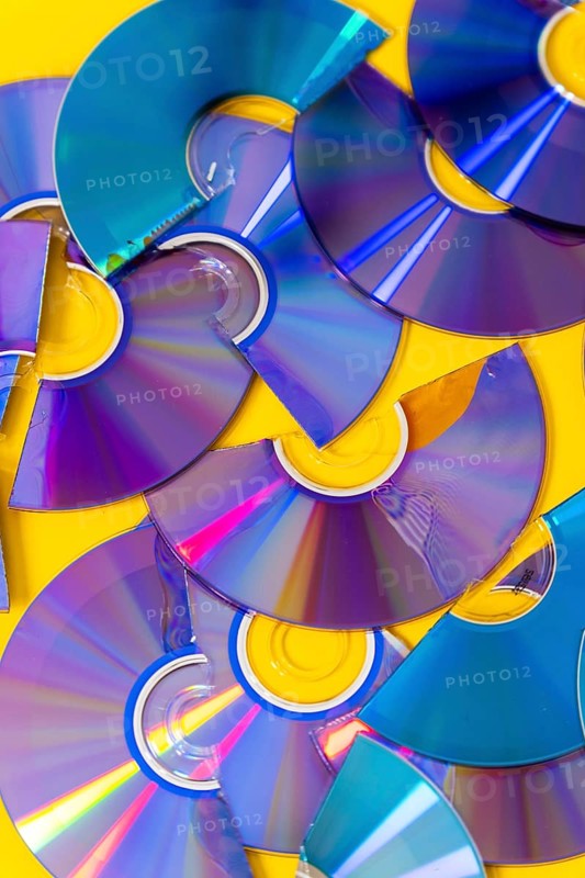 Top view of cut CDs and DVDs against a yellow background