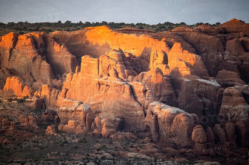 Captivating view of Arches national park' rock formations bathed in warm sunset light. The natural beauty and geological formations create a stunning landscape scene