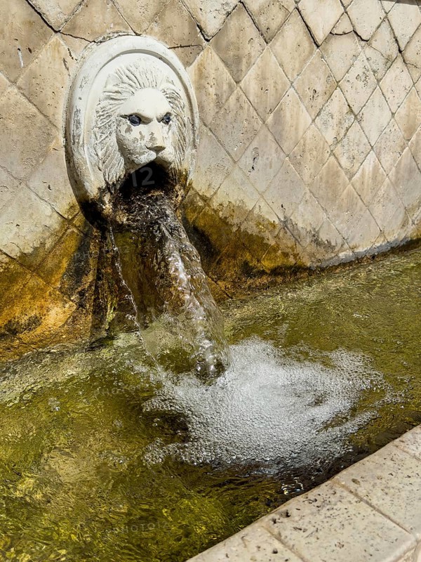 Partial view of large in the picture gargoyle in the form of head of lion lion head below collecting basin of lion fountain Venetian fountain Kefalovrisi with 25 gargoyles for with drinking water on main square of village Spili, Spili, Crete, Greece
