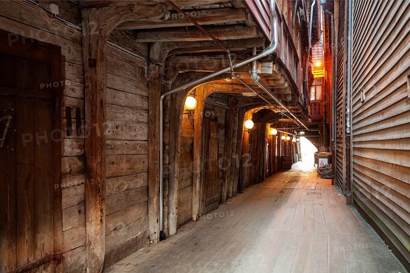 Summer day exploring behind facades in Bryggen Bergen, narrow lanes, colorful wooden buildings, historic trade stores, Vestland, Norway