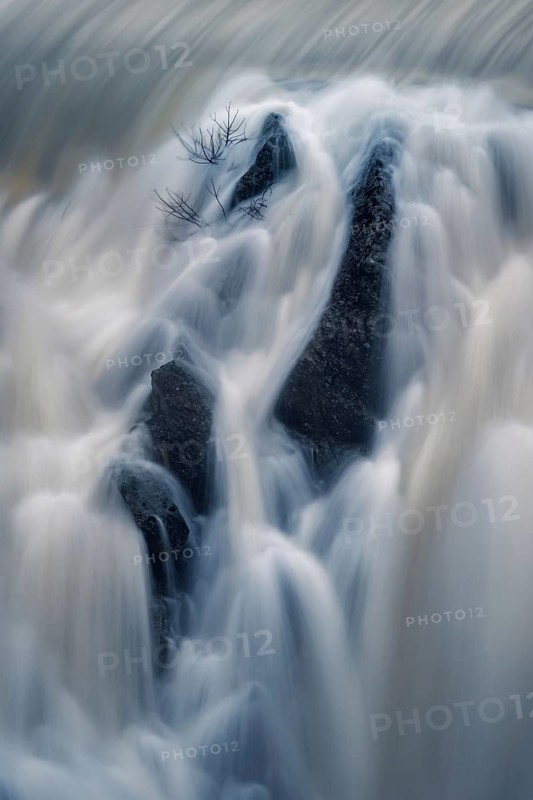 Ethereal view of water cascading over rocks in a long exposure shot, capturing the silky texture of the flowing water at Presa o Embalse del Villar in Madrid