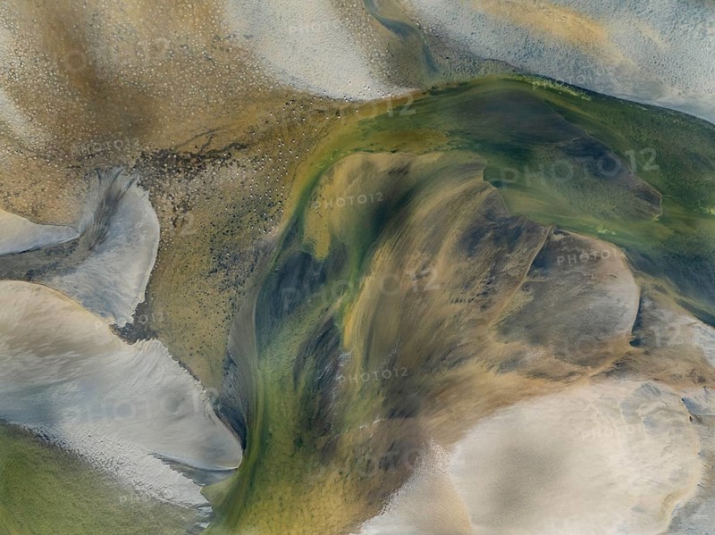 Streams and marshes at low tide in the wetlands of the Walvis Bay lagoon. In the distance Greater Flamingos (Phoenicopterus ruber). Aerial view. Drone shot. Walvis Bay, Namibia