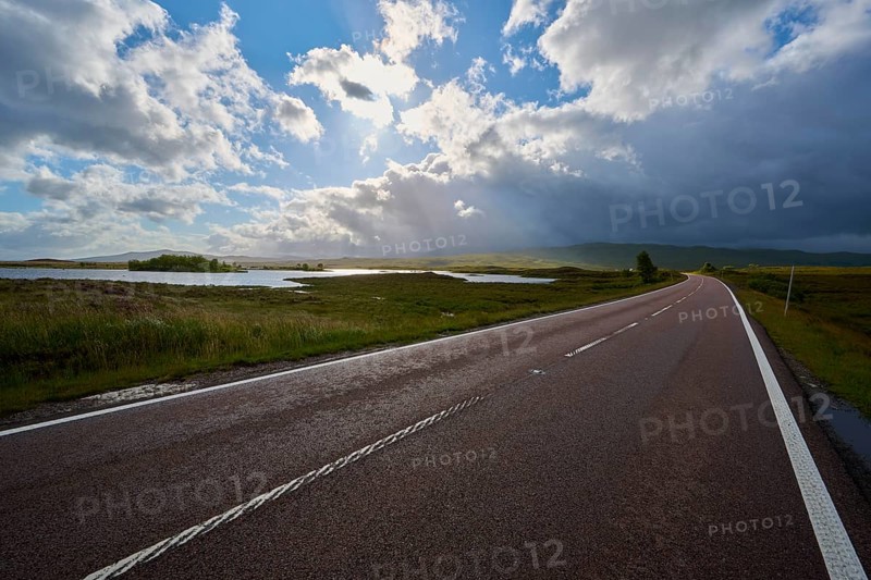 An expansive road leads along picturesque lakes under vivid and dramatic skies, Rannoch Moor, Bridge of Orchy, Scotland, United Kingdom, Great Britain