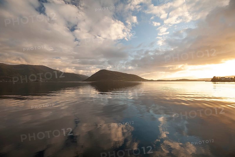 Golden hour light over the harbor and mountains. Summer sunset, Rosendal Port, Vestland, Norway