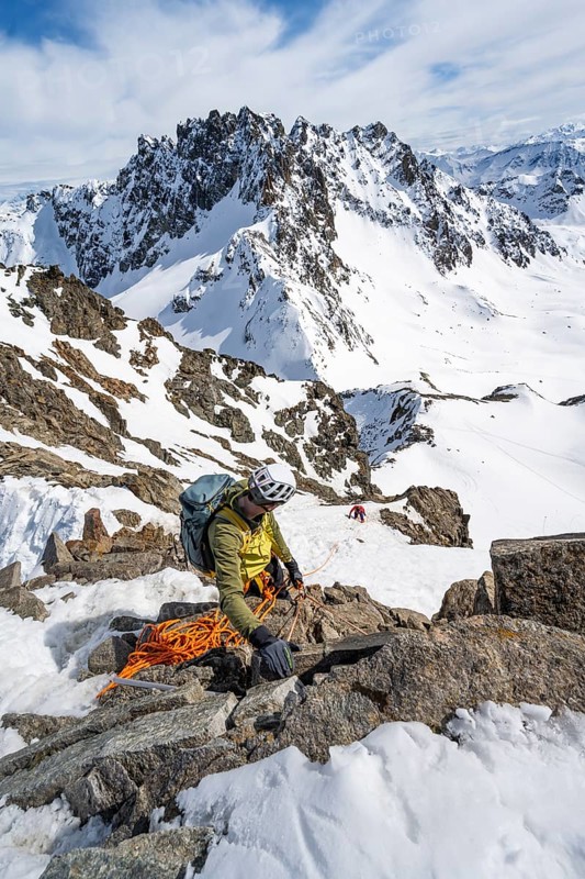 Mountaineer belaying on a steep snow slope, belaying on a rope, ascent to the summit of Piz Grialetsch in winter, view of mountain panorama with snow, Grisons Haute Route, Albula Alps, Rhaetian Alps, Grisons, Switzerland