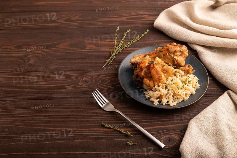 Fried Turkey Wing with spices and thyme on plate on brown wooden background and linen textile. side view, copy space