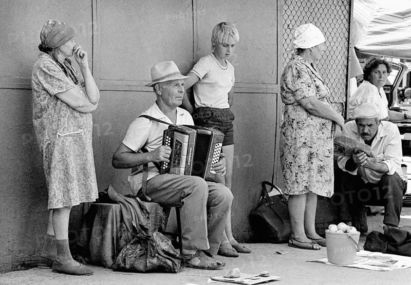 With an accordion, a family man plays folk songs at a vegetable market in Alma Ata, his son is watching, Alma Ata, Kazakhstan
