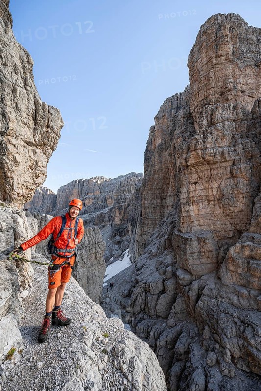 Mountaineer climbs an exposed rock band in the secured via ferrata Bocciere Centrale, Brenta Mountains, Parco Naturale Brenta-Adamello, Trentino, Italy
