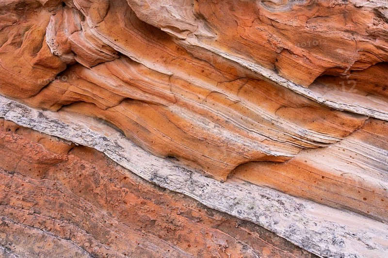 Close-up of natural sandstone with abstract layers and textures in earthy tones. The intricate patterns create a mesmerizing visual, highlighting the beauty of geological formations
