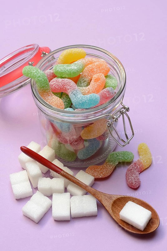 Lots of colorful jelly sweets in glass containers and sugar cubes, sugar consumption