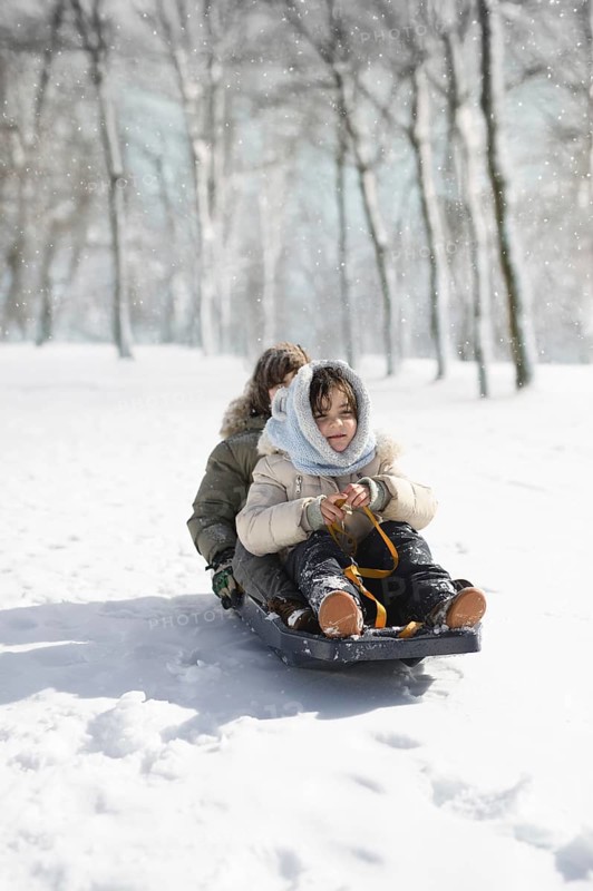 Two children joyfully sled through the snow-covered woods at Sierra Nevada Ski Resort in Granada. Dressed warmly, they enjoy the thrill of a winter adventure