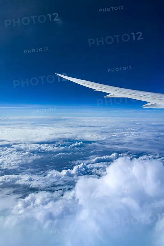 View from the aircraft window during a flight over India with the airline Etihad. Blue sky and cloud structures over the sea, wing of a Boeing 787 aircraft