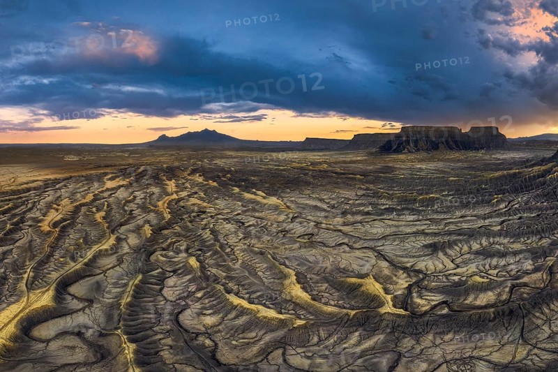 A breathtaking view of sunset casting dramatic shadows across the wrinkled landscape of Factory Butte, Utah, highlighting the unique geological formations and vast plains