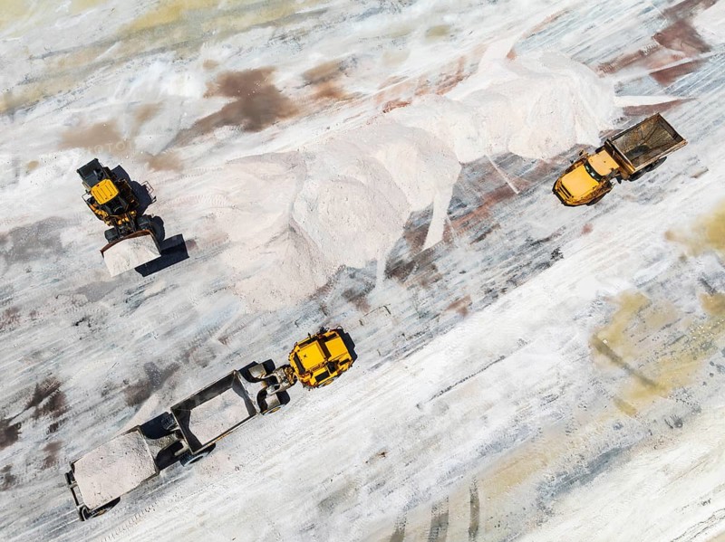 Excavator and lorries and at a harvesting pan of the Walvis Bay Salt works. Aerial view. Drone shot. Walvis Bay, Namibia