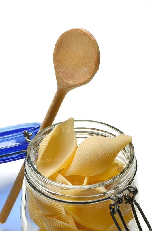 Conchiglione in glass jar with cooking spoon, Italian pasta variety