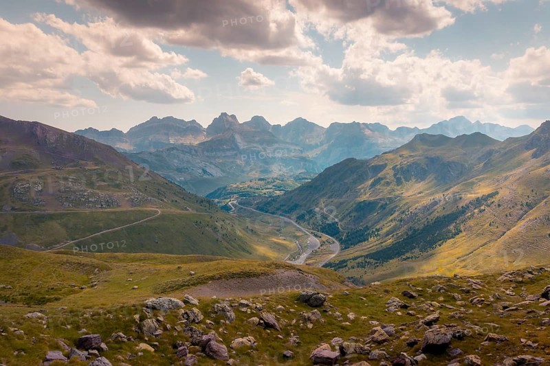 A breathtaking view of a serene mountain landscape with winding rivers and lush green valleys in the Pyrenees. The scene captures the beauty of nature under a partly cloudy sky in summer