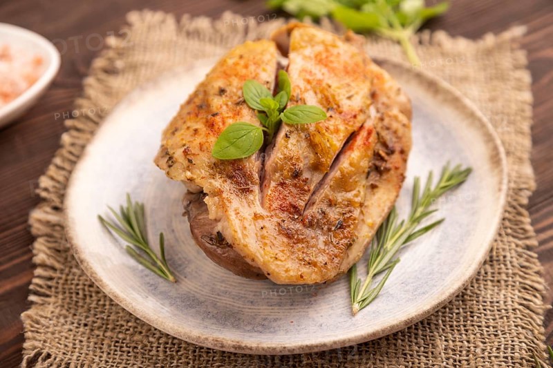 Fried Turkey Thigh with spices and rosemary on plate on brown wooden background and linen textile. side view, close up, selective focus