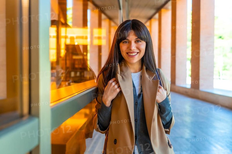 Young woman student standing confidently in a bright modern university corridor, smiling and ready for academic success, career growth and new beginnings in higher education