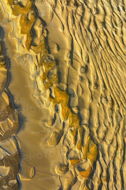 Aerial view of wind sculpted patterns in golden sandy terrain. Natural textures create abstract landscapes, highlighting the beauty and complexity of nature art