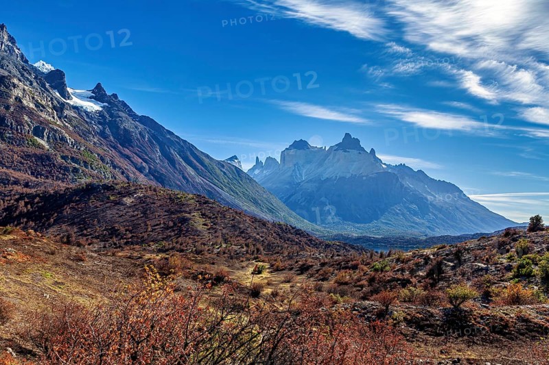 Majestic mountains rise under a sky with decorative cloud shapes over a vast landscape, The landscape of the Torres del Paine National Park in Patagonia Chile