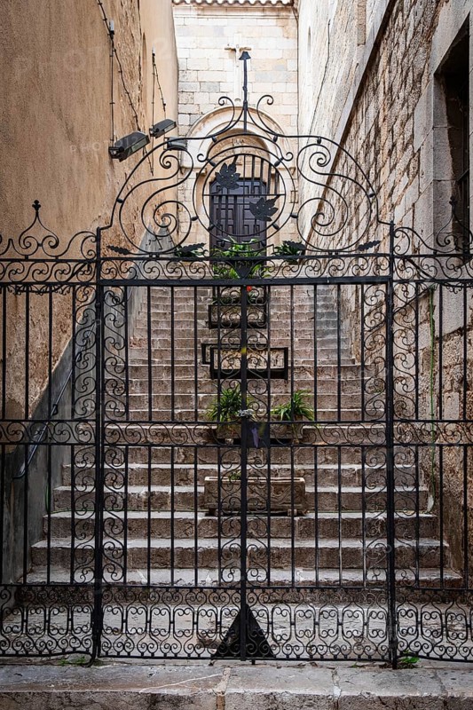 Wrought iron Tor tor, behind it stone flower pots on a staircase to a church in Figueras, Spain