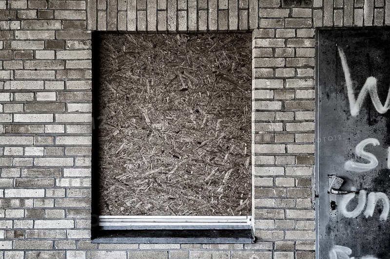 Old building with brick walls and a window covered with OSB panels