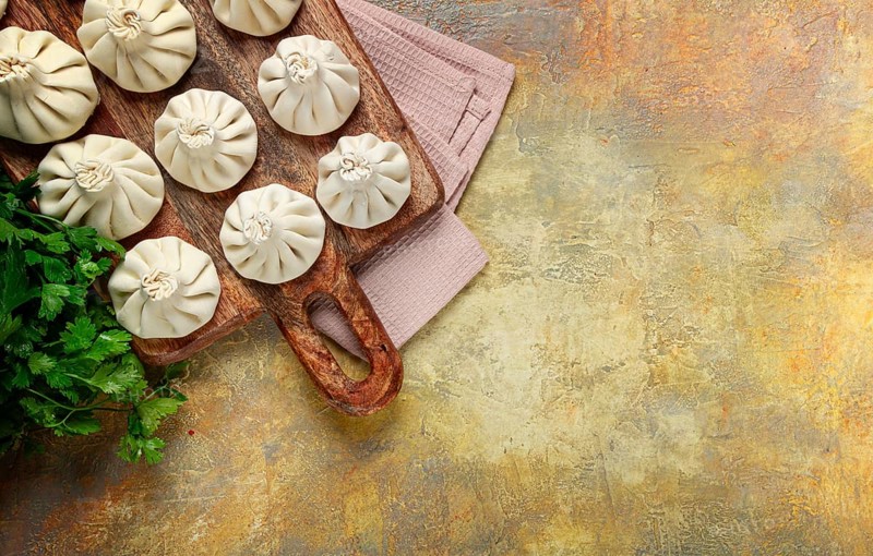 Freshly frozen raw khinkali, on a wooden chopping board, top view, Georgian cuisine, no people