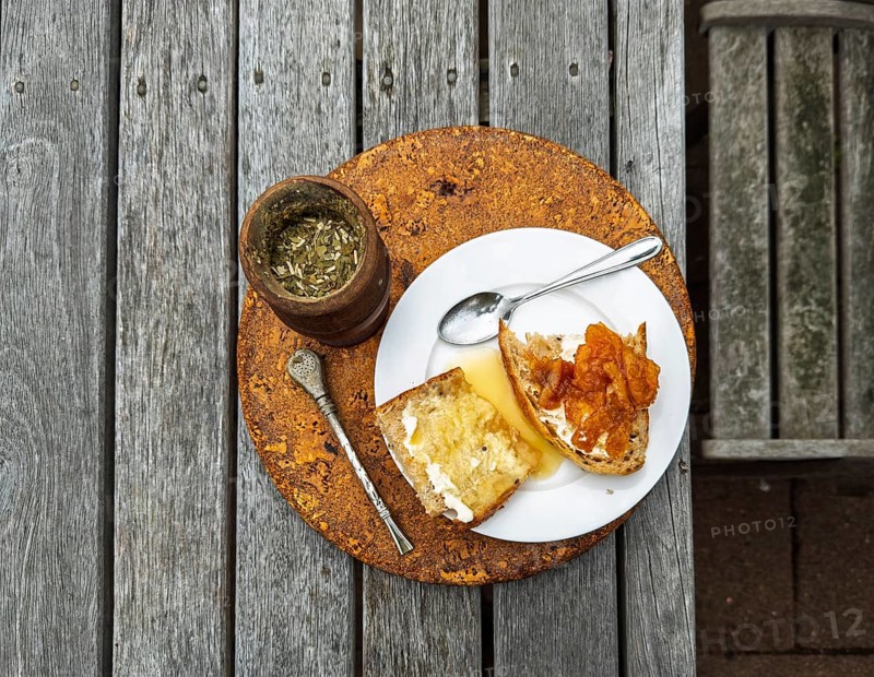 A rustic breakfast scene features slices of toast topped, accompanied by a cup of herbal tea. The wooden table enhances the cozy atmosphere