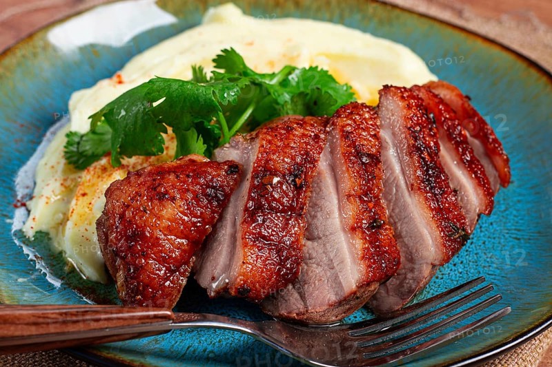 Roast duck breast, sliced with mashed potatoes, on a plate, close-up, no people