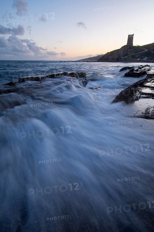 Experience the breathtaking sunset on the coast of Tarifa, Cadiz. The sky is painted with warm hues, while gentle waves crash against rocky shores, creating a serene seascape