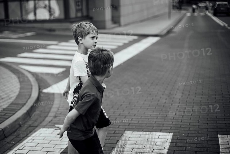 Two boys walk the pedestrian crossing on the street
