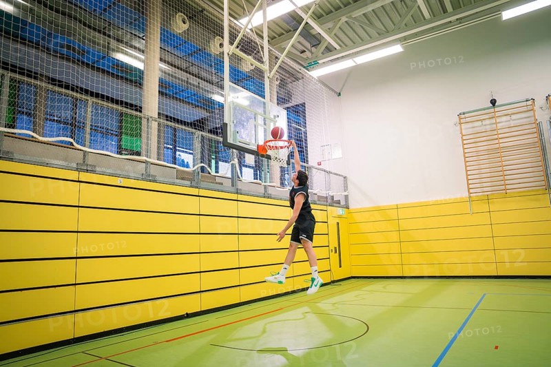 A basketball player throws the ball in a yellow gym, basketball TSV Calw, Germany