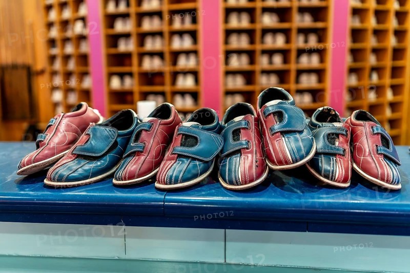 Red and blue bowling shoes resting on a counter, inviting bowlers to rent and enjoy an exciting game at the bowling alley