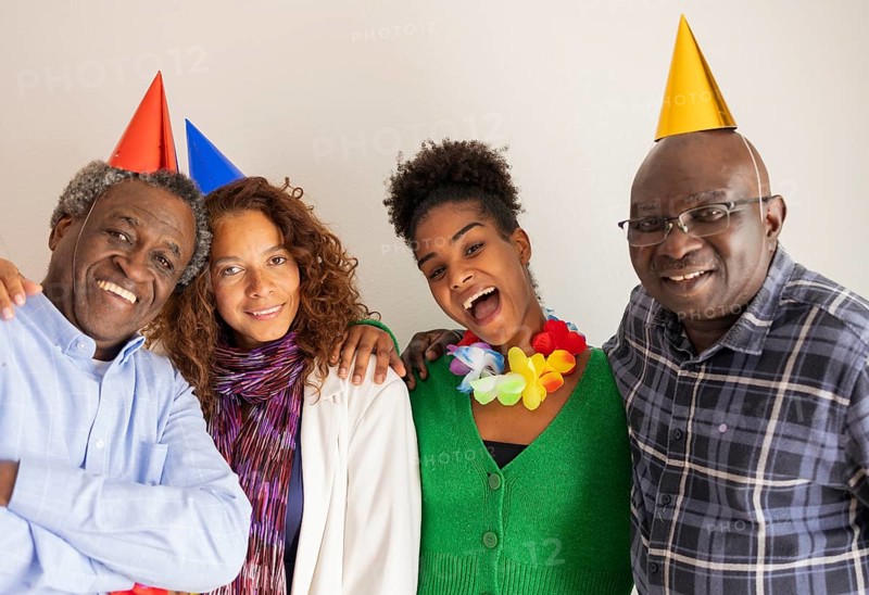 Happy friends wearing colorful party hats and leis, celebrating a birthday with wide smiles. A joyful moment of togetherness and fun on a special day