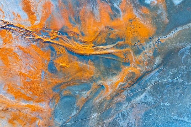 A mesmerizing aerial view of a natural landscape transformed into an abstract multicolour canvas, revealing intricate patterns and bold swaths of orange and blue