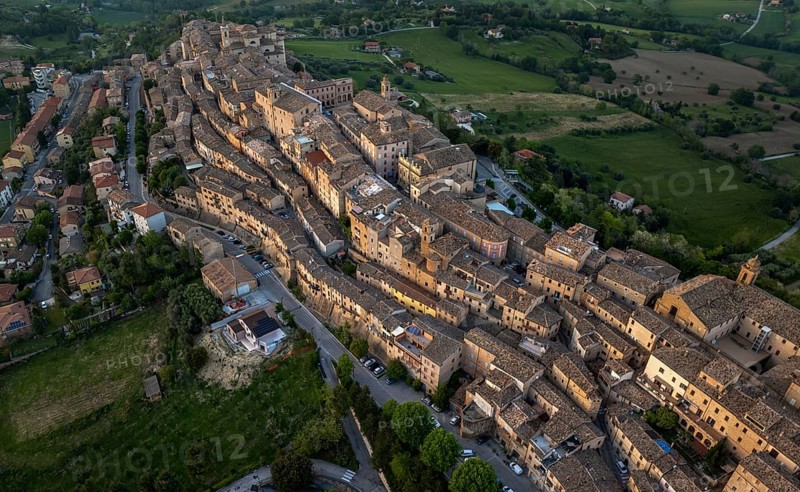 Aerial view of Treia, Italy, highlighting its remarkable medieval architecture nestled amid lush fields. This panorama captures the unique layout of the historic town