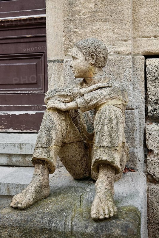 Sculpture in front of the old school building, art in public space, stone figure, sculpture by the artist Ulla Frenger, depiction of a pupil, building from 1867 made of Gönningen tuff, former elementary and secondary school, today the Gönningen branch of the town library, Gönningen, Reutlingen district, Baden-Württemberg, Germany