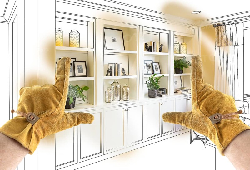 Male Contractor Hands Framing Completed Section of Built In Shelving Over Drawing