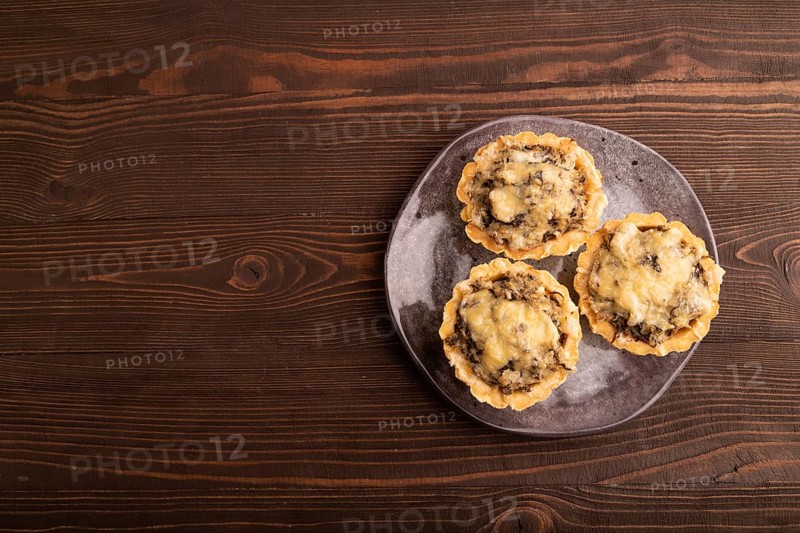 Tartlets with meat and cheese on brown wooden background. top view, flat lay, copy space