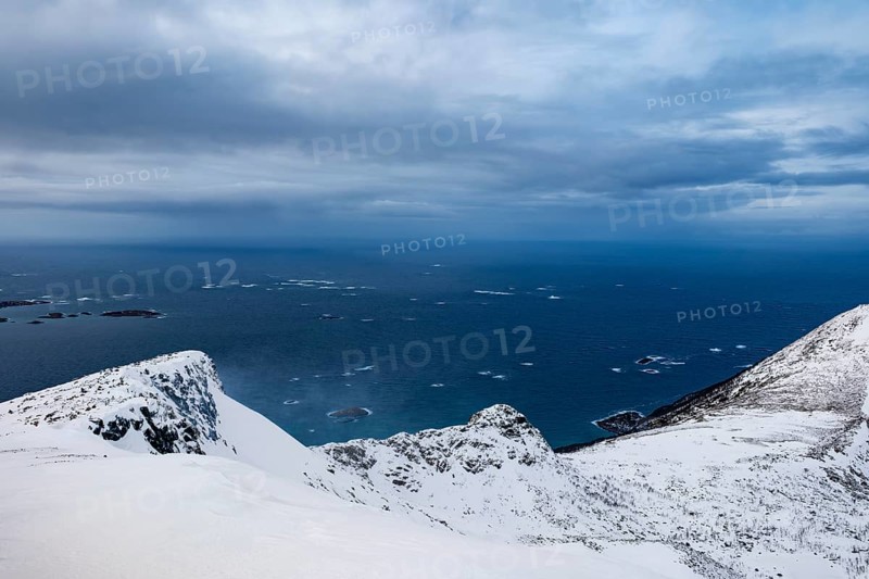 View of open sea from snow-capped peaks, Senja Island, Troms, Norway