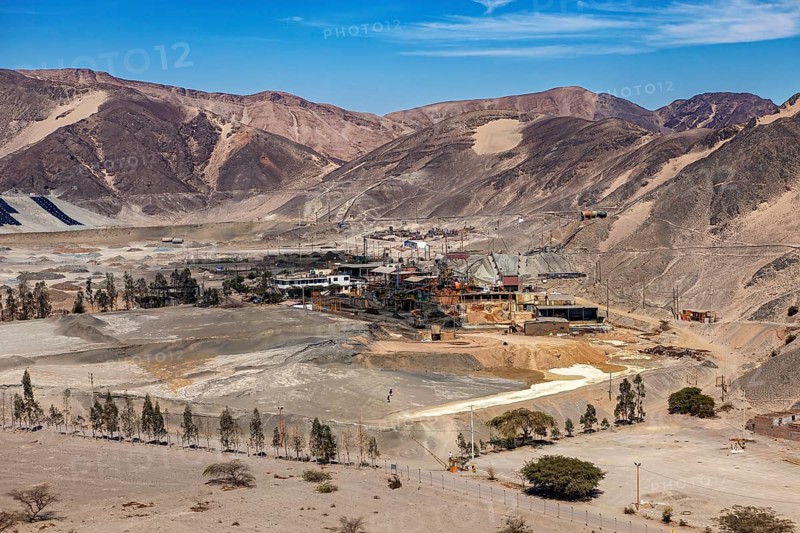 Desert landscape with mountain ranges and a mine in the foreground under a clear sky, an ore mine in the desert near Nasca in Peru