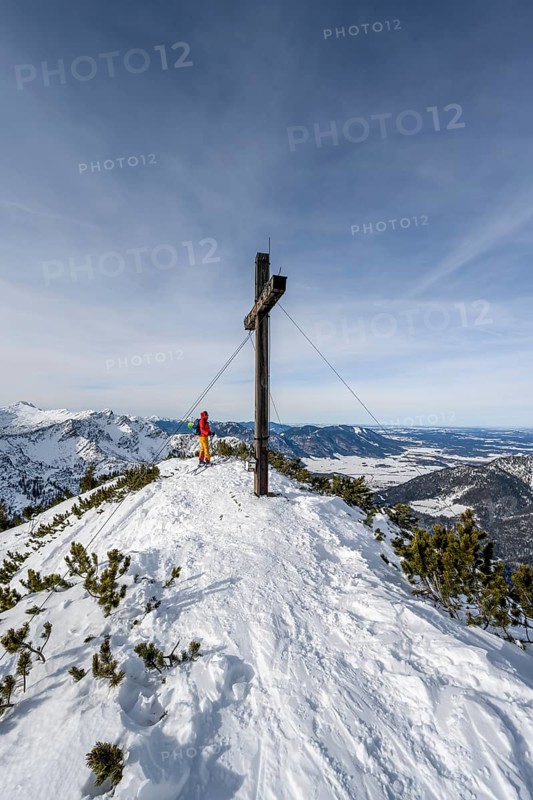 Ski tourer at the summit of the Simetsberg with summit cross, mountain panorama, Estergebirge, Bavarian Prealps, Bavaria Germany