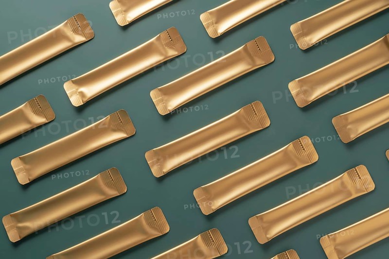 Aesthetic arrangement of gold jelly collagen sachets on a muted green background. Ideal for skin health and beauty routines, these sachets offer a convenient option for daily use