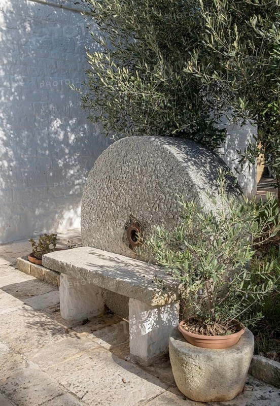 Small stone bench in front of an old millstone, Apulia, Italy