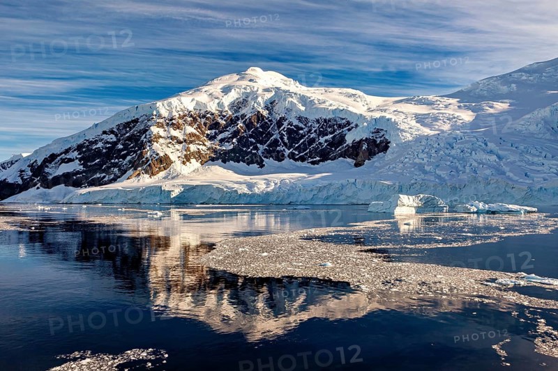 A snow-covered mountain reflected in the calm water, surrounded by a winter landscape, The landscape of Antarctica