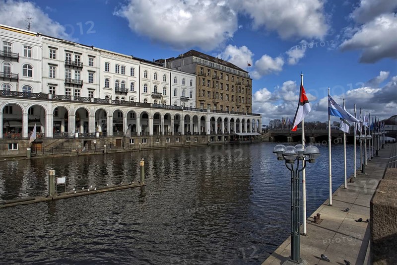 Alster tacades on a canal with flags in the wind and clear sky, Hamburg, Germany