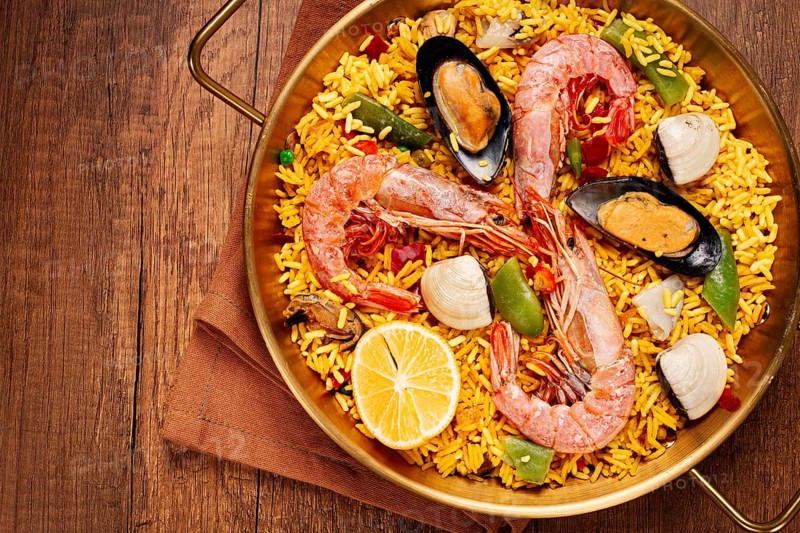Seafood paella, in a frying pan, on a wooden table, no people