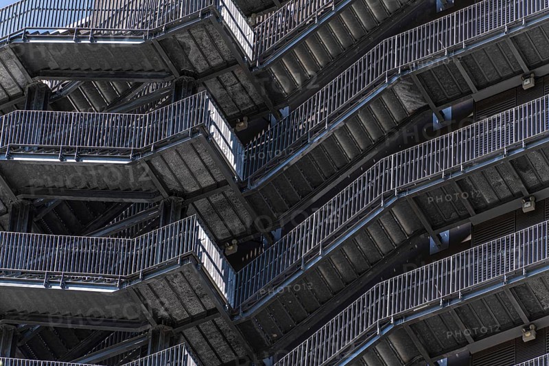 A striking image of urban metal stairs exhibiting a geometric design. The intricate architecture and repeating patterns create a visually complex and modern urban scene