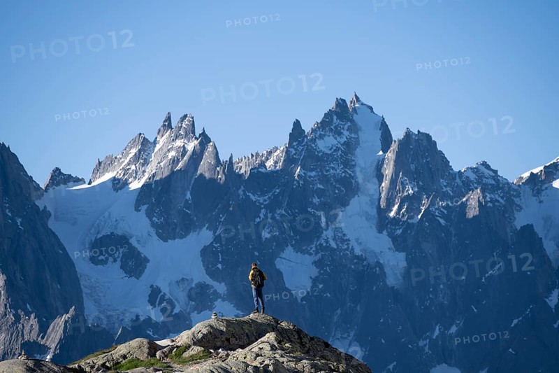 Young man in front of impressive mountain landscape in morning light, pointed rocky icy mountain peaks, Mont Blanc massif, Chamonix-Mont-Blanc, Haute-Savoie, France